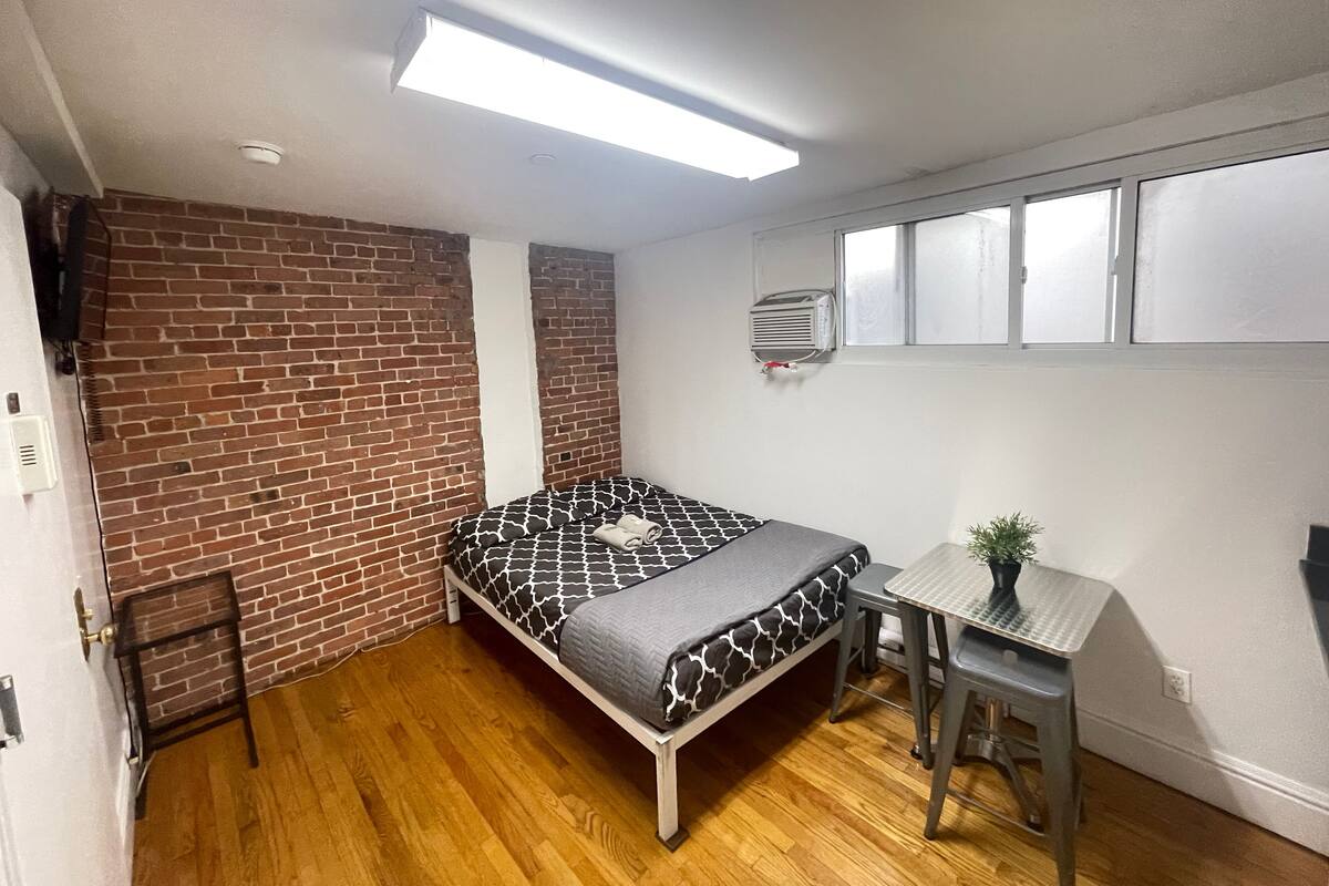 Una habitación pequeña con cama, un escritorio y una ventana.