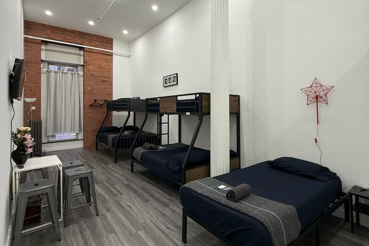 Una habitación moderna y bien iluminada con literas, un escritorio con silla y una mesita con un florero.