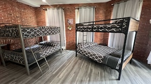 Una habitación con dos literas, una pared de ladrillo y una ventana con cortinas.