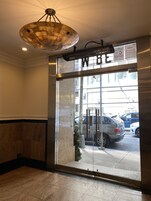A hotel entrance with a glass door, a 'No Smoking' sign, and a view of parked cars outside.