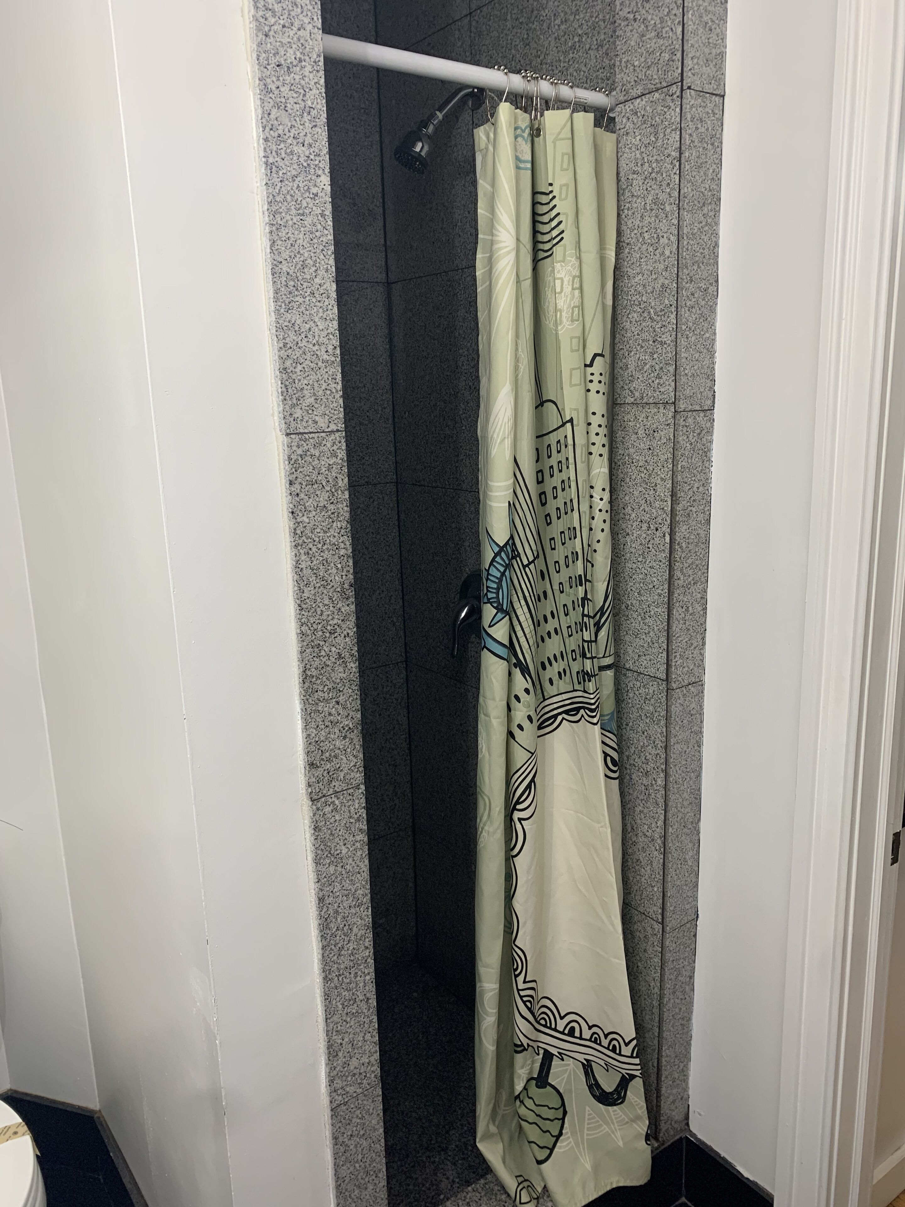 A bathroom with a shower curtain featuring a cityscape design.