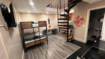 A compact room with bunk beds, a small table, and a staircase.