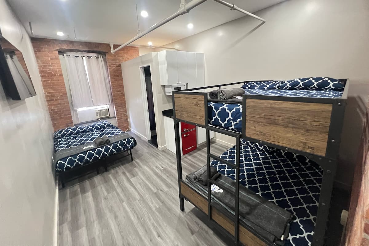 Un dormitorio con literas, una pequeña kitchenette y una pared de ladrillo.