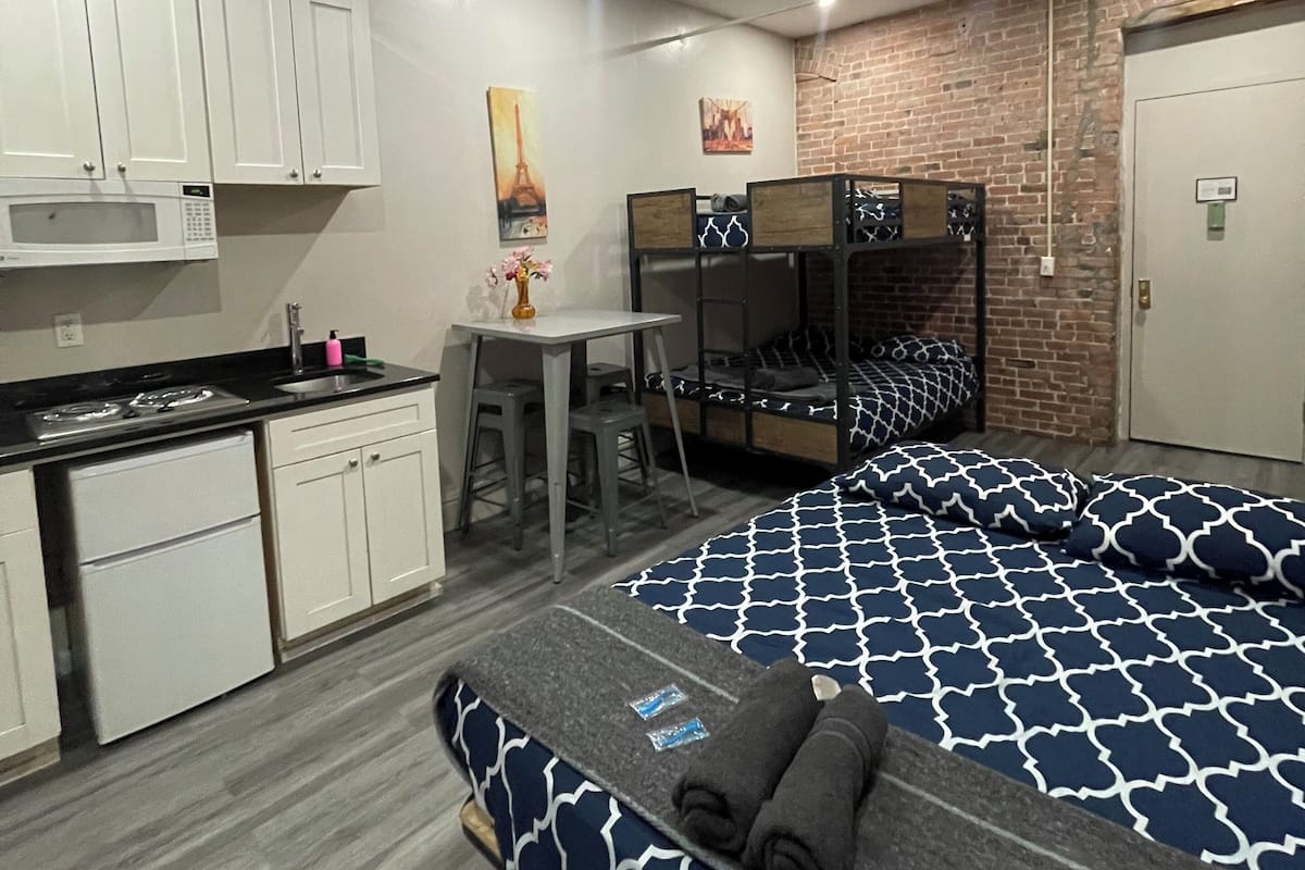 Una habitación de hotel compacta con kitchenette, literas y un pequeño escritorio.