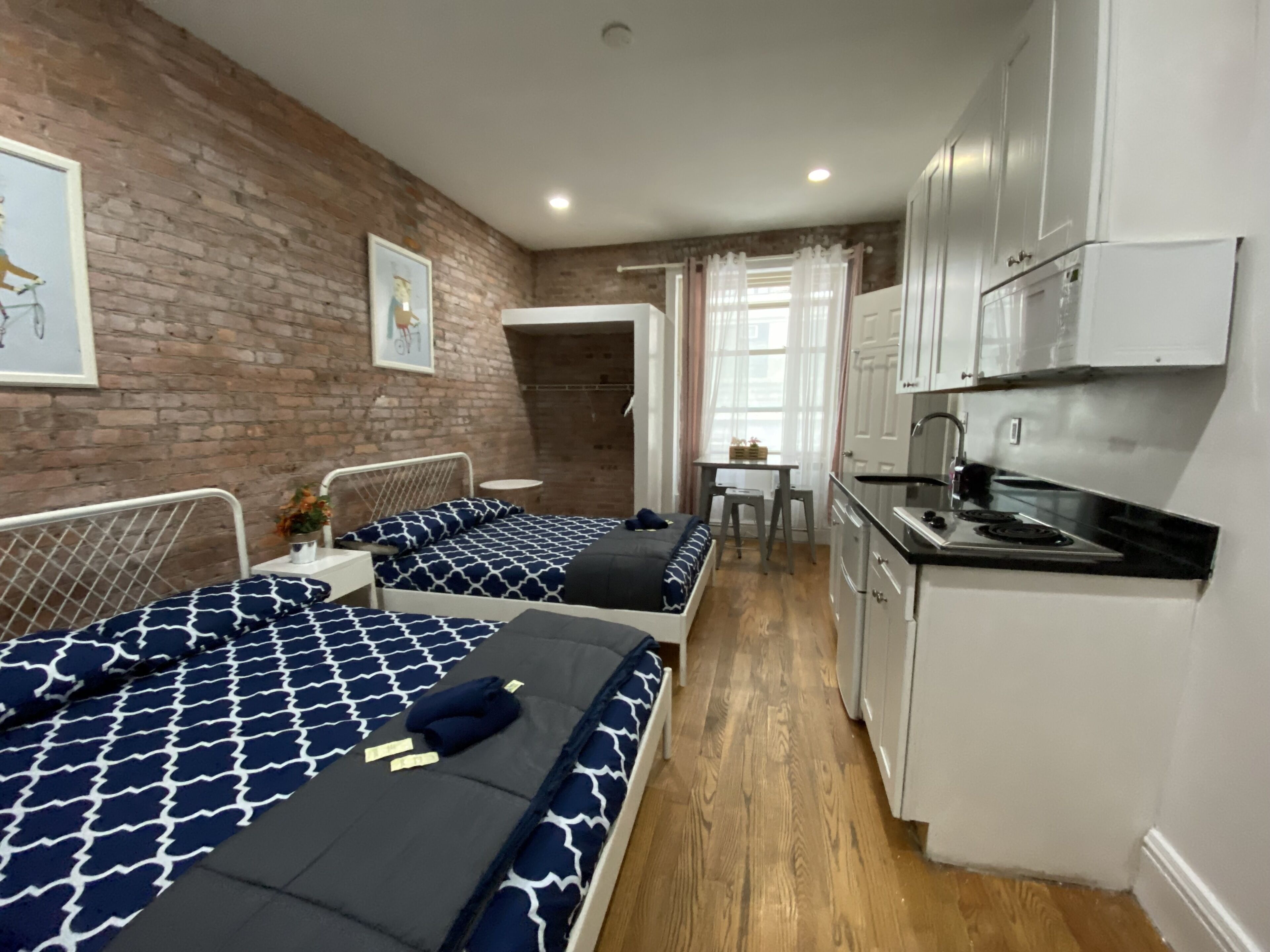 A compact studio apartment with two single beds, a kitchenette, and a small dining area.
