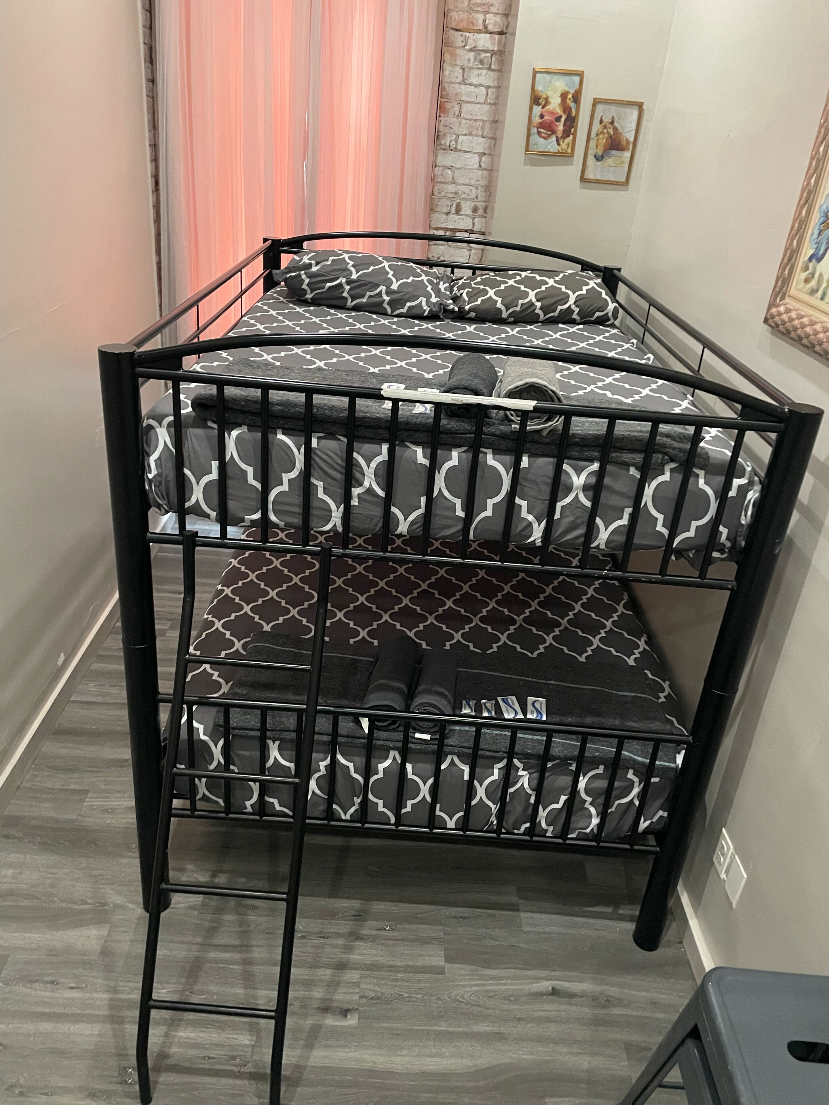Una cama litera con ropa de cama estampada, una escalera y un taburete pequeño.