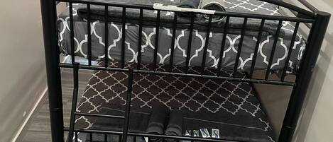 Una cama litera con ropa de cama estampada, una escalera y un taburete pequeño.