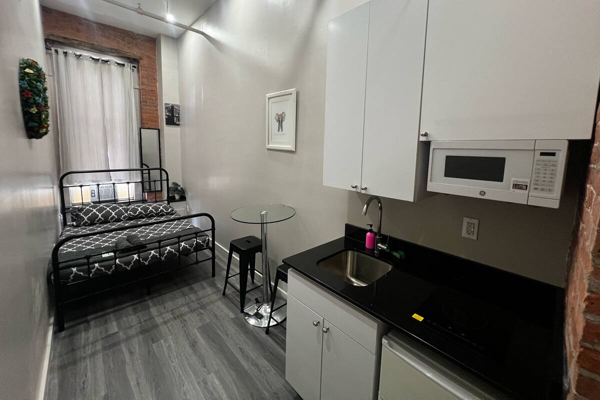 Un apartamento estudio pequeño con cama, kitchenette y un comedor.