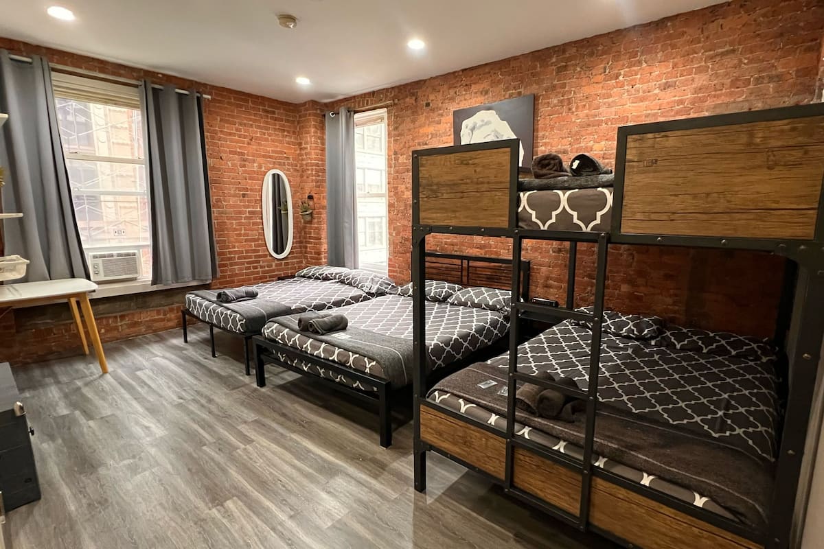 Una habitación con dos literas, un escritorio, una silla y una ventana con cortinas.
