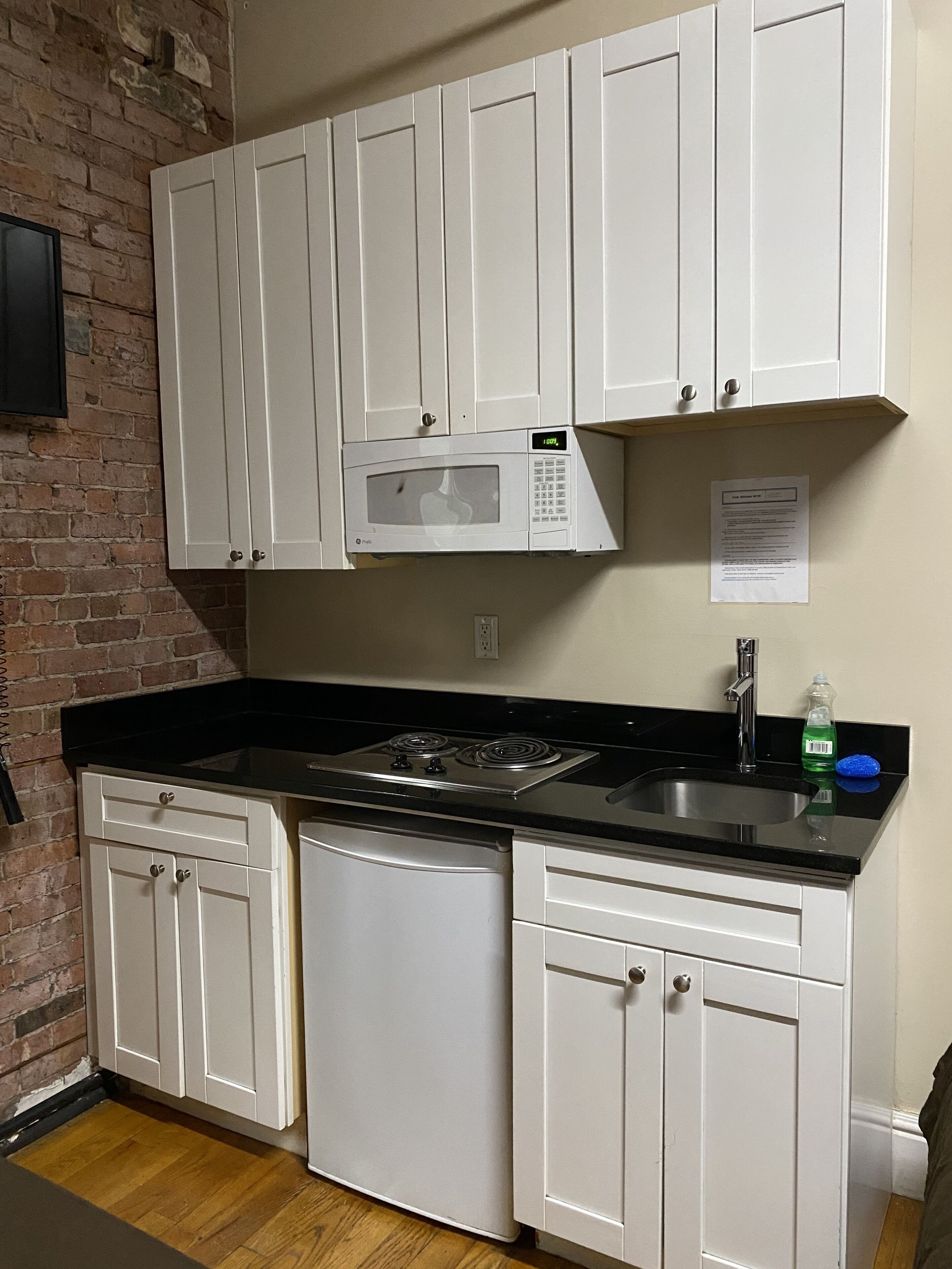 A kitchen with white cabinets, a microwave, a stove, and a sink.
