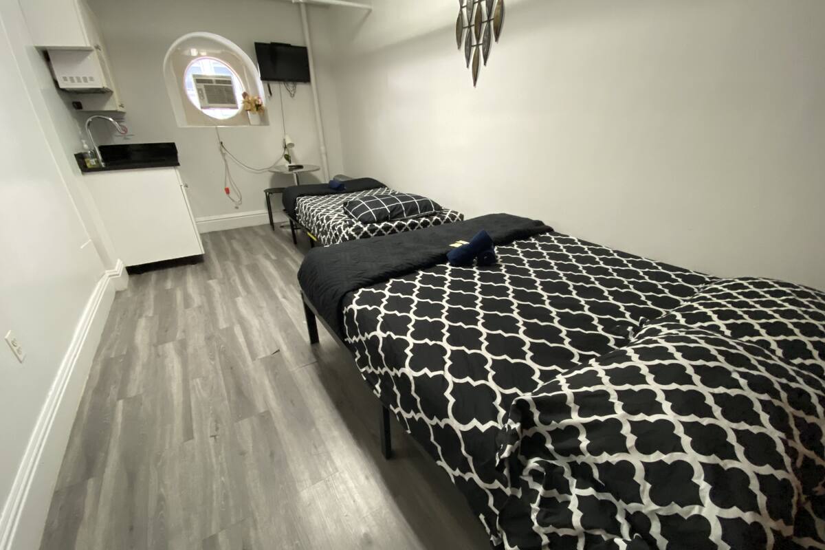 Un dormitorio con dos camas, una mesita, un espejo y una ventana.