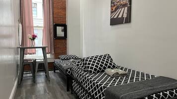 A compact hotel room with a bed, a desk, and a chair.