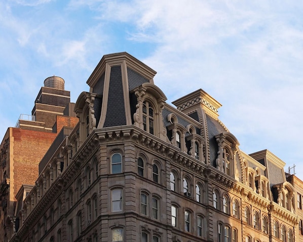 Un edificio histórico con detalles arquitectónicos ornamentales, incluyendo múltiples ventanas y elementos decorativos en la fachada.