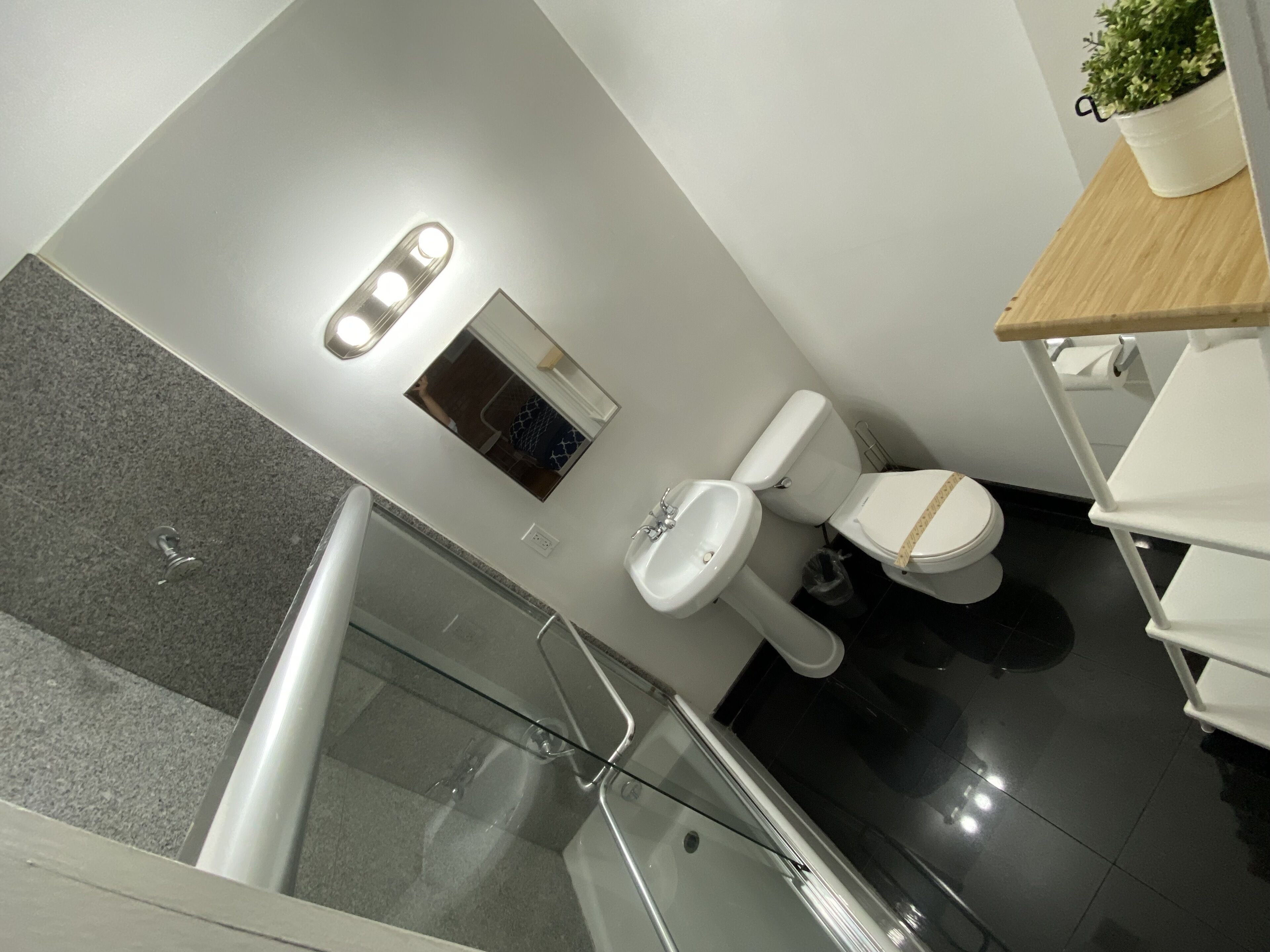 A modern bathroom with a toilet, sink, and a small mirror.