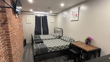 A compact bedroom with a bed, a small table, and a desk.