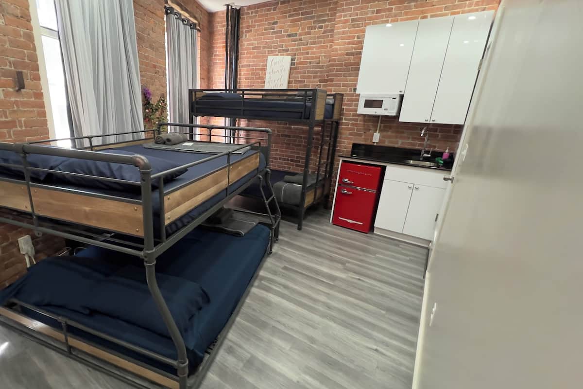 Habitación con literas y una zona de cocina, que incluye un microondas y un refrigerador.