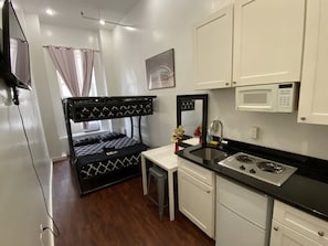 Una kitchenette compacta con microondas, estufa y lavabo.