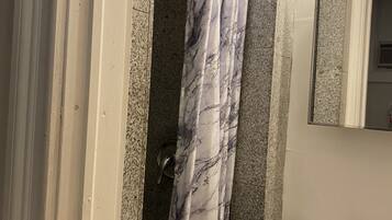 A bathroom with a marble shower curtain, a sink, and a mirror.