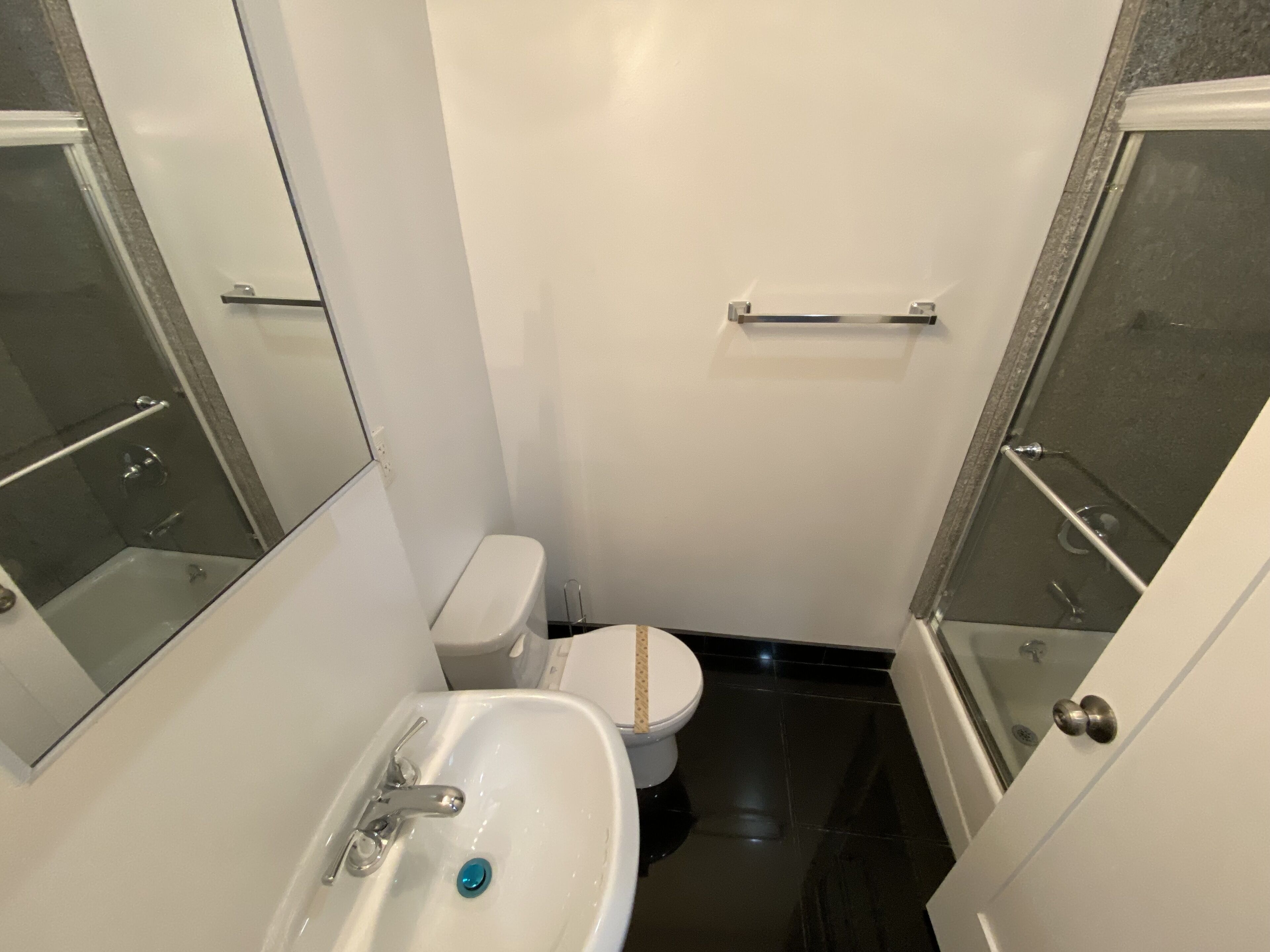 A small, modern bathroom with a white toilet, a sink, and a glass shower enclosure.