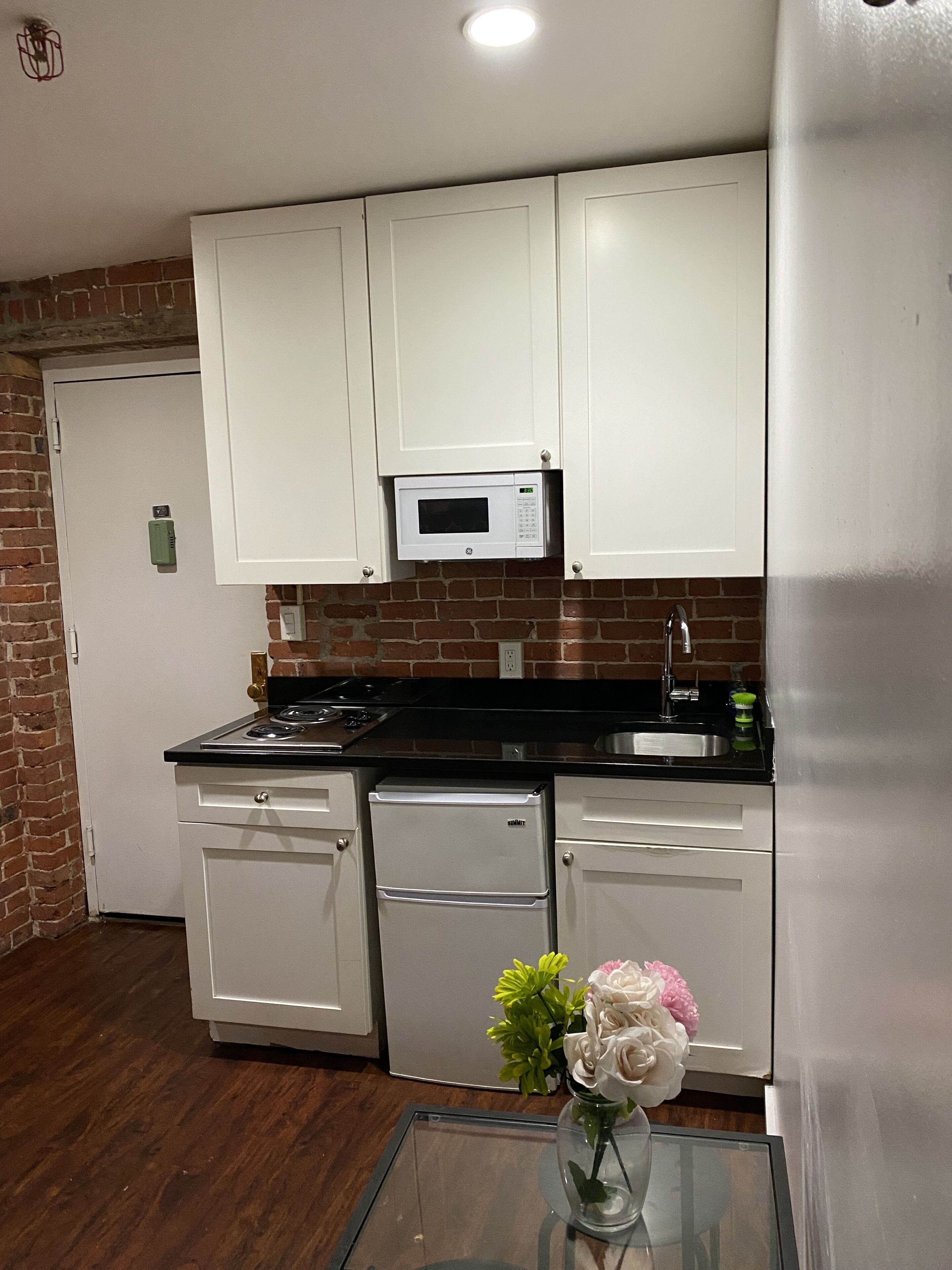 A compact kitchen with white cabinets, a microwave, a stove, and a dishwasher.