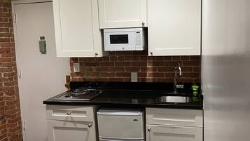 A compact kitchen with white cabinets, a microwave, a stove, and a dishwasher.