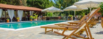 Una piscina al aire libre, sombrillas, sillones reclinables de piscina