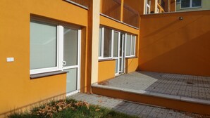 A yellow building with multiple windows and a small outdoor area with a tiled floor.