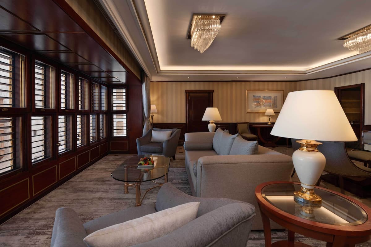 A spacious living room with a large window, a chandelier, and a sofa set.