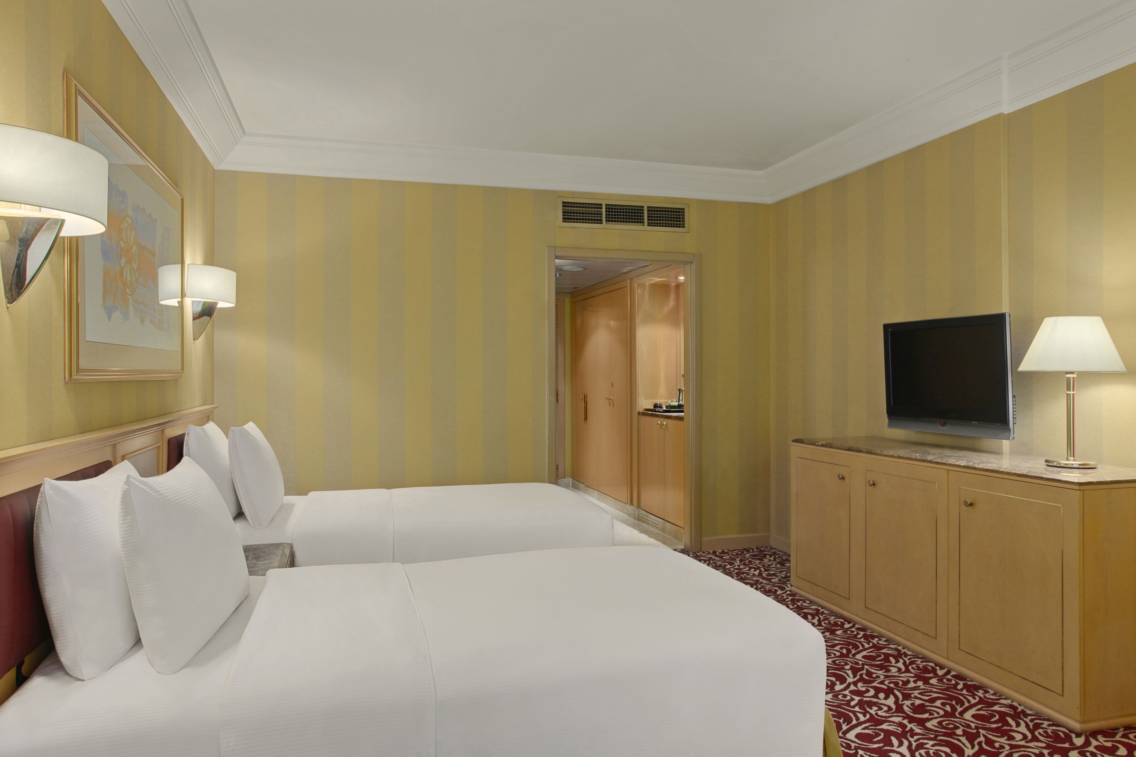 A hotel room with two beds, a television, and a cabinet.