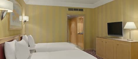 A hotel room with two beds, a television, and a cabinet.