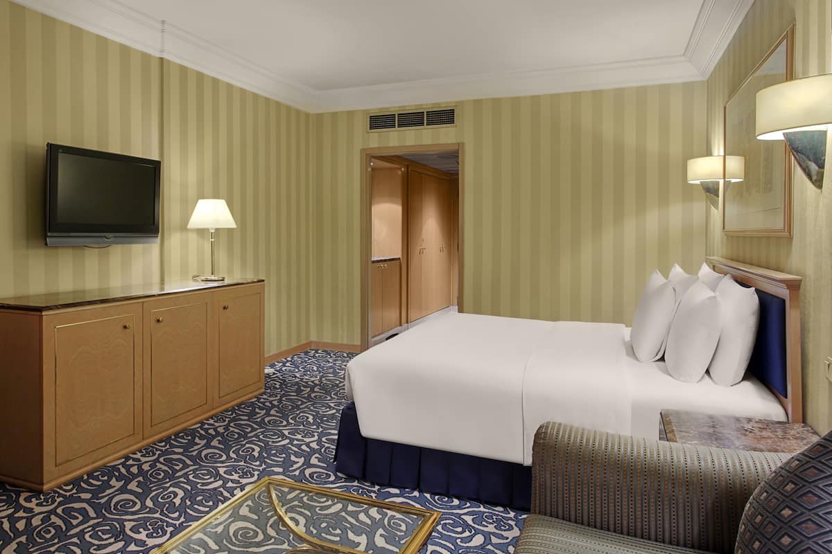 A hotel room with a bed, a television, a desk, and a chair.