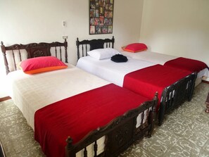 Une chambre avec trois lits, chacun doté d’une tête de lit en bois et d’une literie rouge.