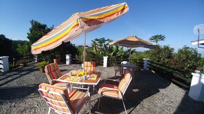 Une terrasse extérieure avec des parasols à rayures, une table dressée avec de la nourriture et des chaises à rayures.
