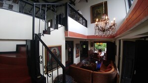 Un interno a più livelli con una scala, una sala da pranzo con un lampadario e un quadro appeso al muro.
