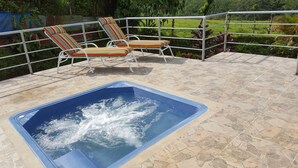 Una vasca idromassaggio con due poltrone da relax a righe e un corrimano in metallo.