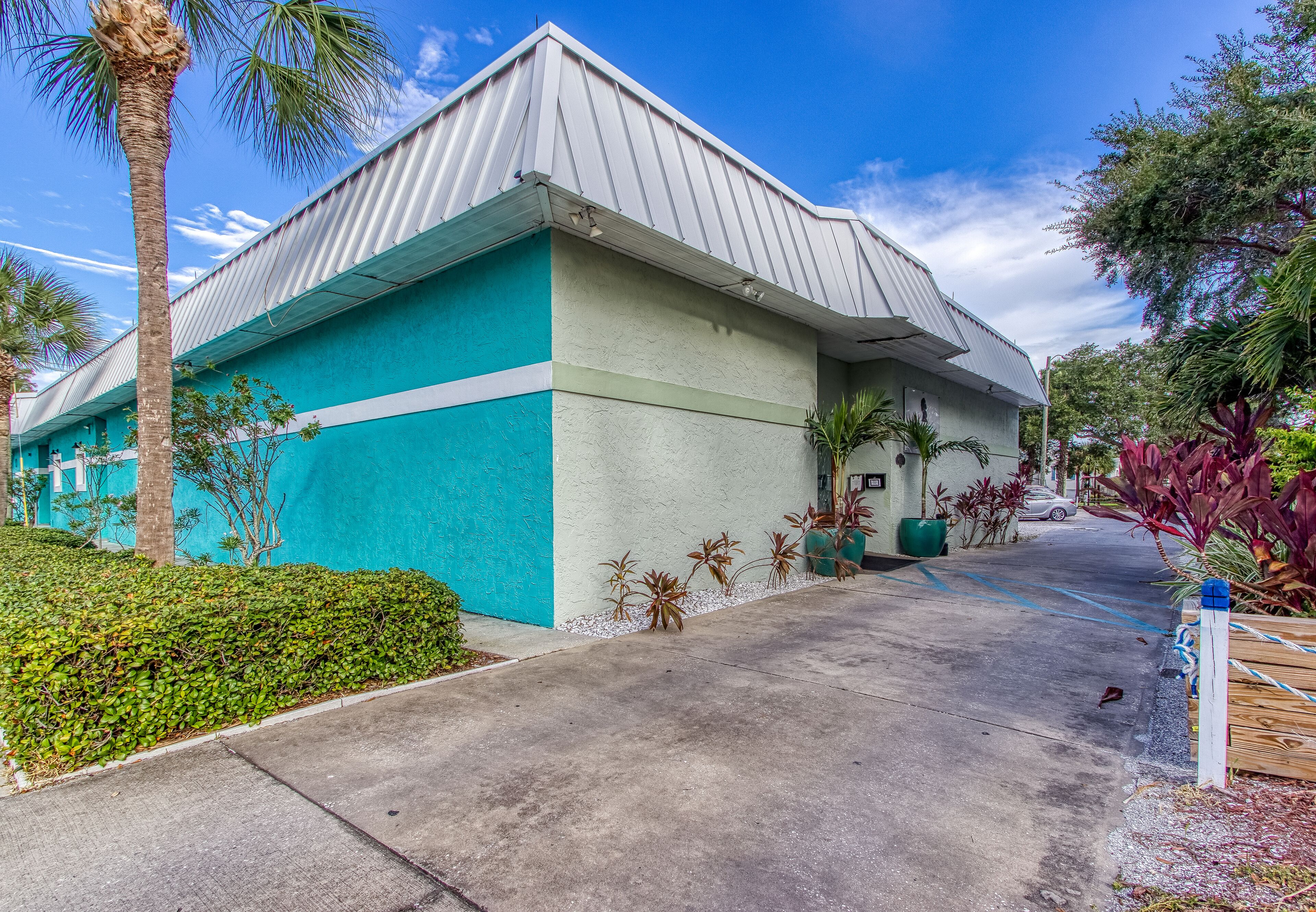 A building with a blue and white exterior, a parking lot, and surrounding greenery.