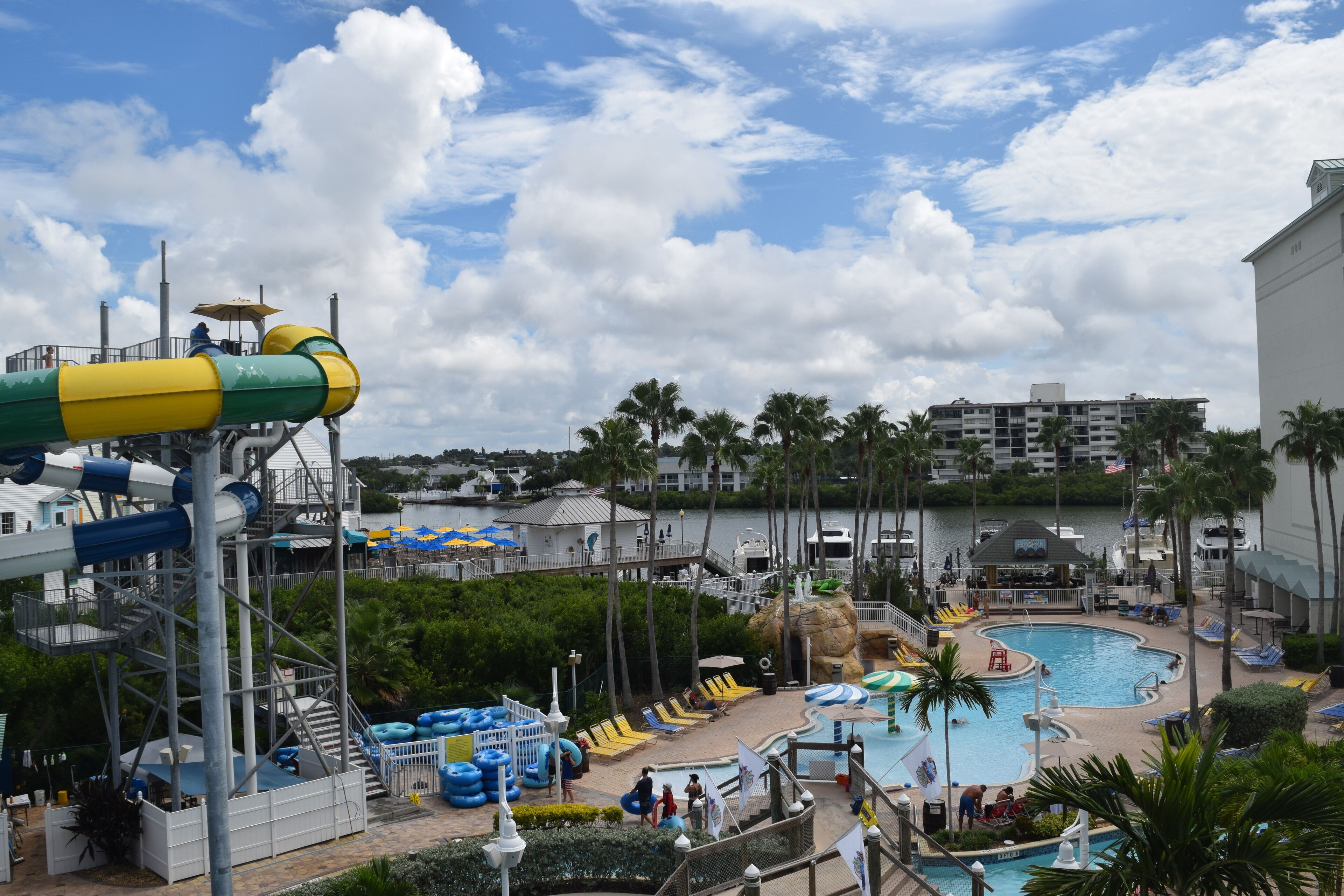A water park with a large pool, slides, and palm trees.