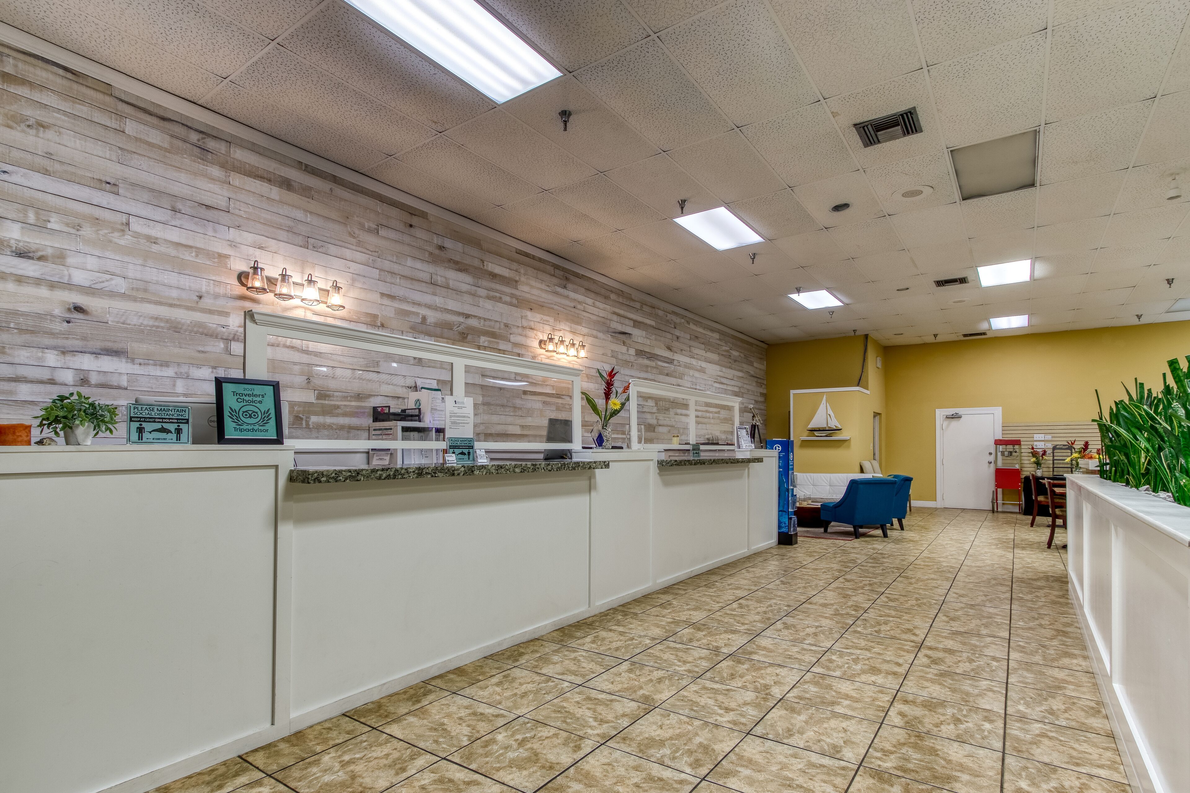 A reception area with a wooden wall, a reception desk, a blue chair, and a yellow wall in the background.