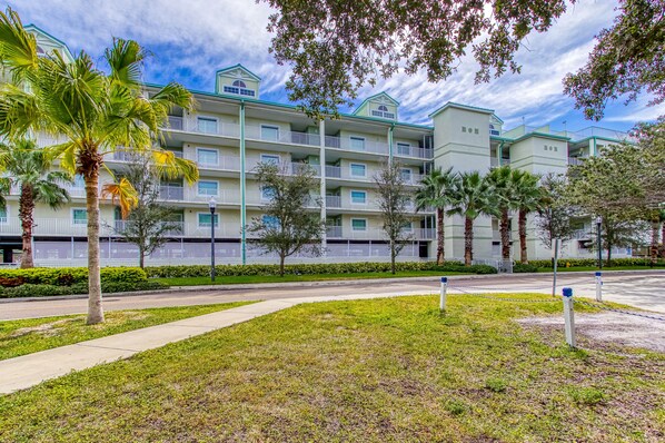 A multi-story hotel with balconies, palm trees, and a well-maintained lawn. - Harbourside Resort, a New Hotel Collection Property   (Indian Rocks Beach)