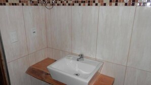 Un baño con un lavamanos blanco, encimera de madera y salpicadero de azulejos.
