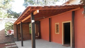 Un espacio al aire libre techado con pared de ladrillo y pérgola de madera.