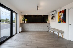 Ein moderner Empfangsbereich mit großem Fenster, einer Rezeption, einer Bank und einem Gemälde an der Wand.