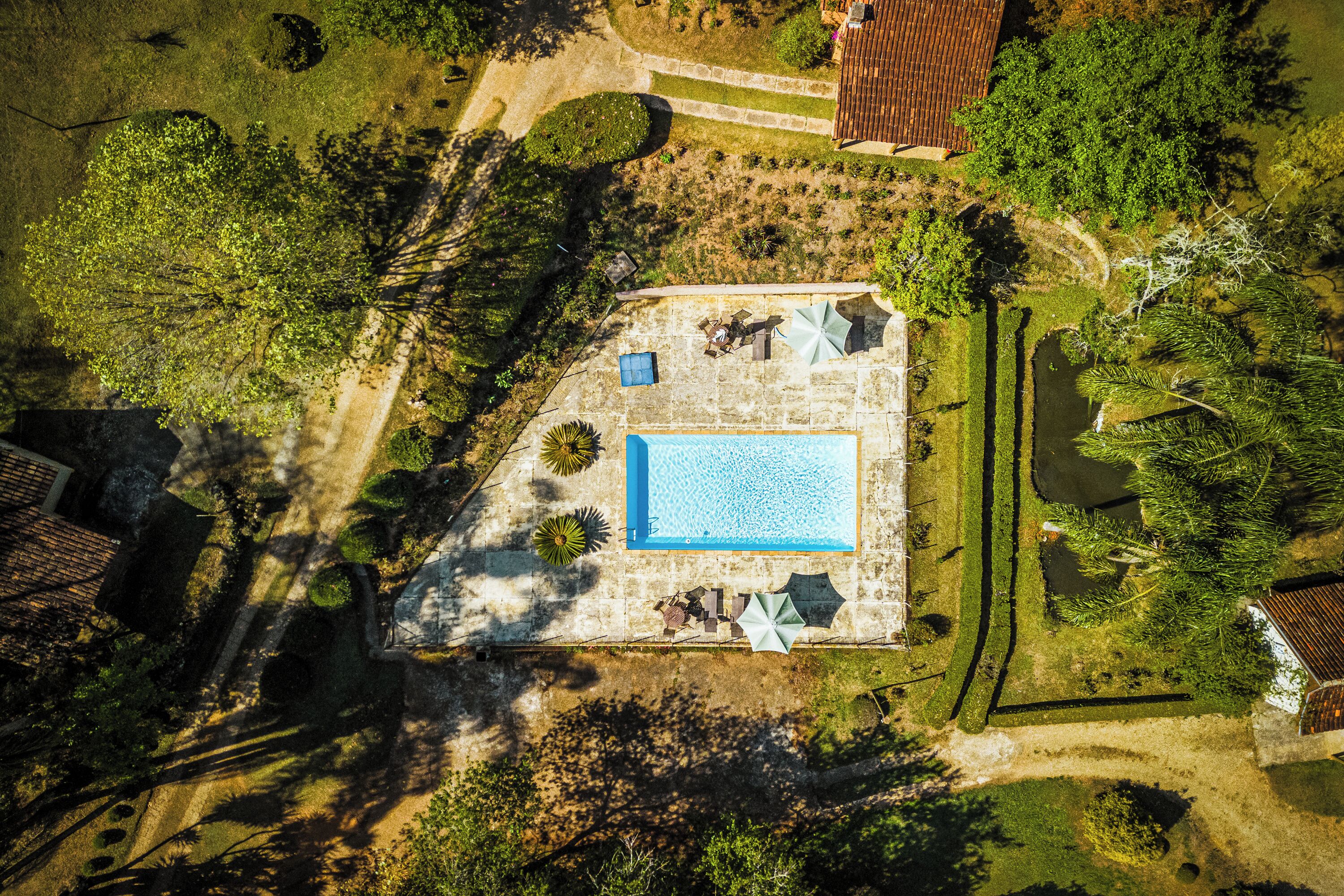 Vue aérienne d’une propriété dotée d’une piscine, de mobilier de jardin et d’un espace verdoyant.