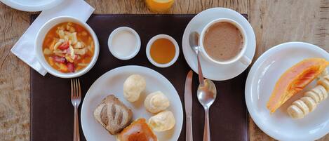Une table en bois dressée pour le petit-déjeuner, avec une variété d’aliments et de boissons.