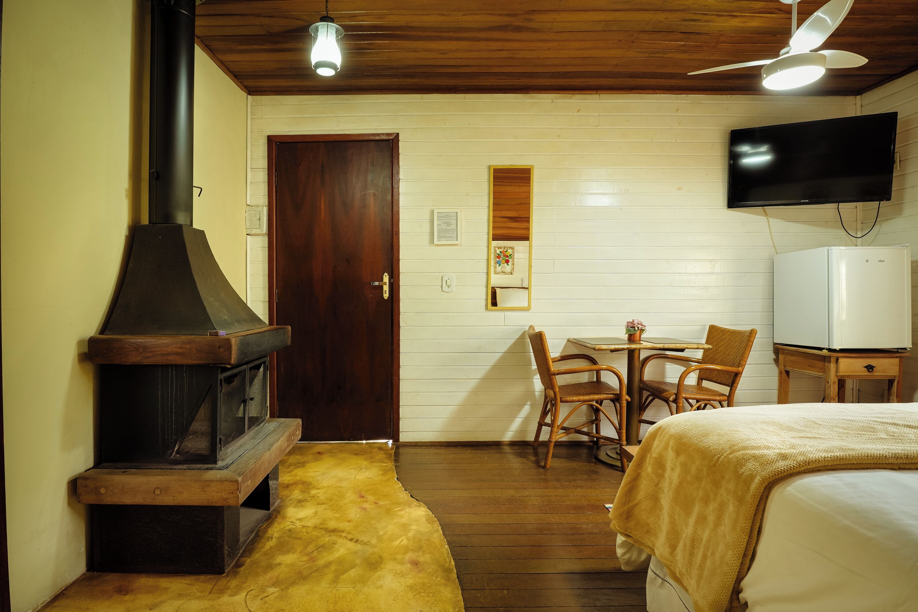 Una habitación con estufa de leña, una cama, televisión y comedor.