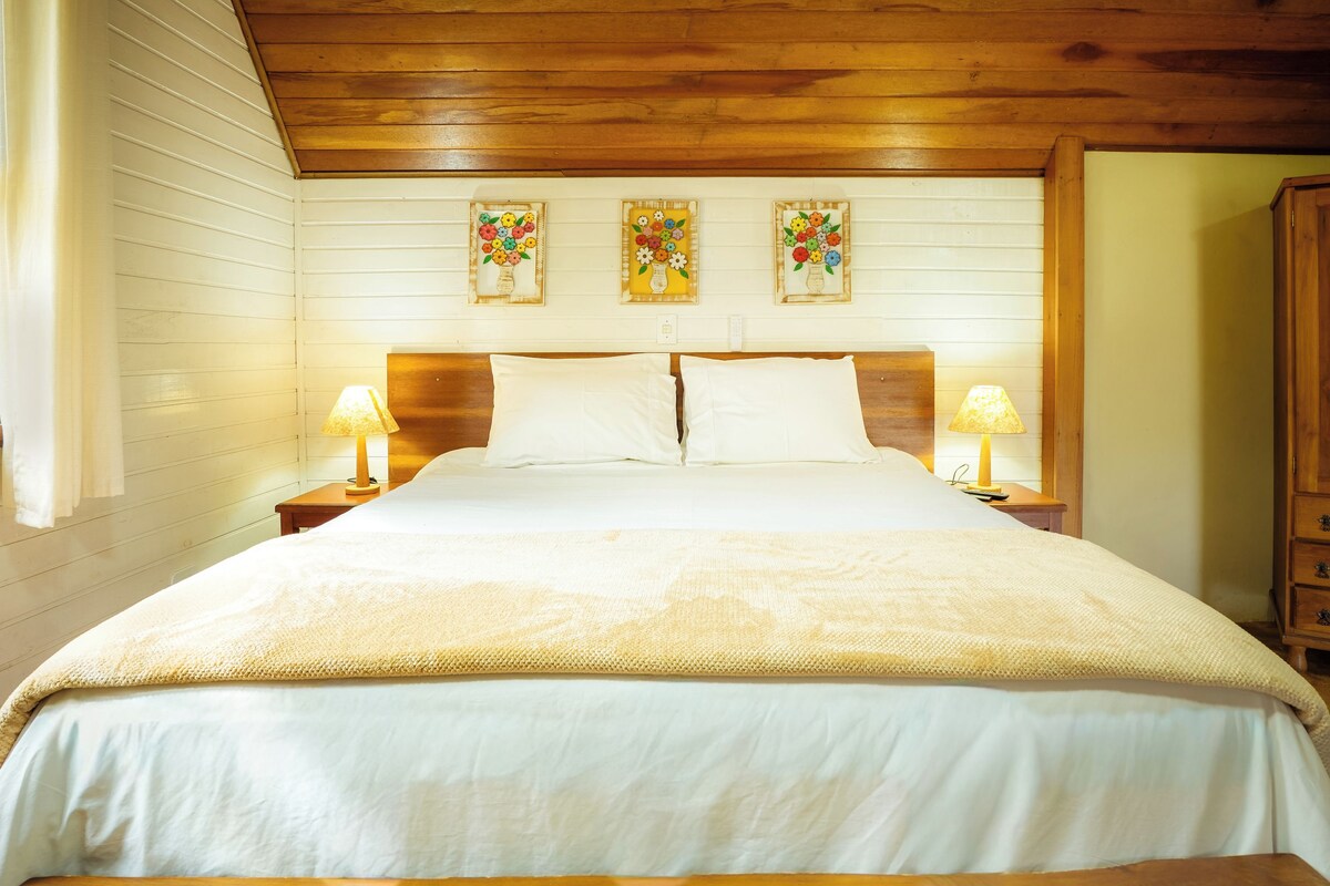A large bed with white linens, wooden headboard, and two bedside lamps.