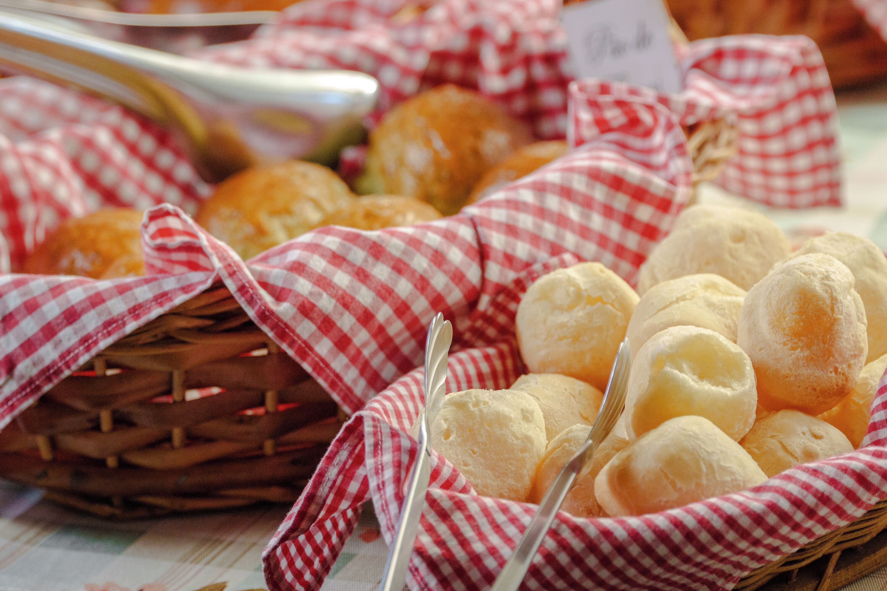 Un panier de petits pains sur une table recouverte d’une nappe à carreaux.