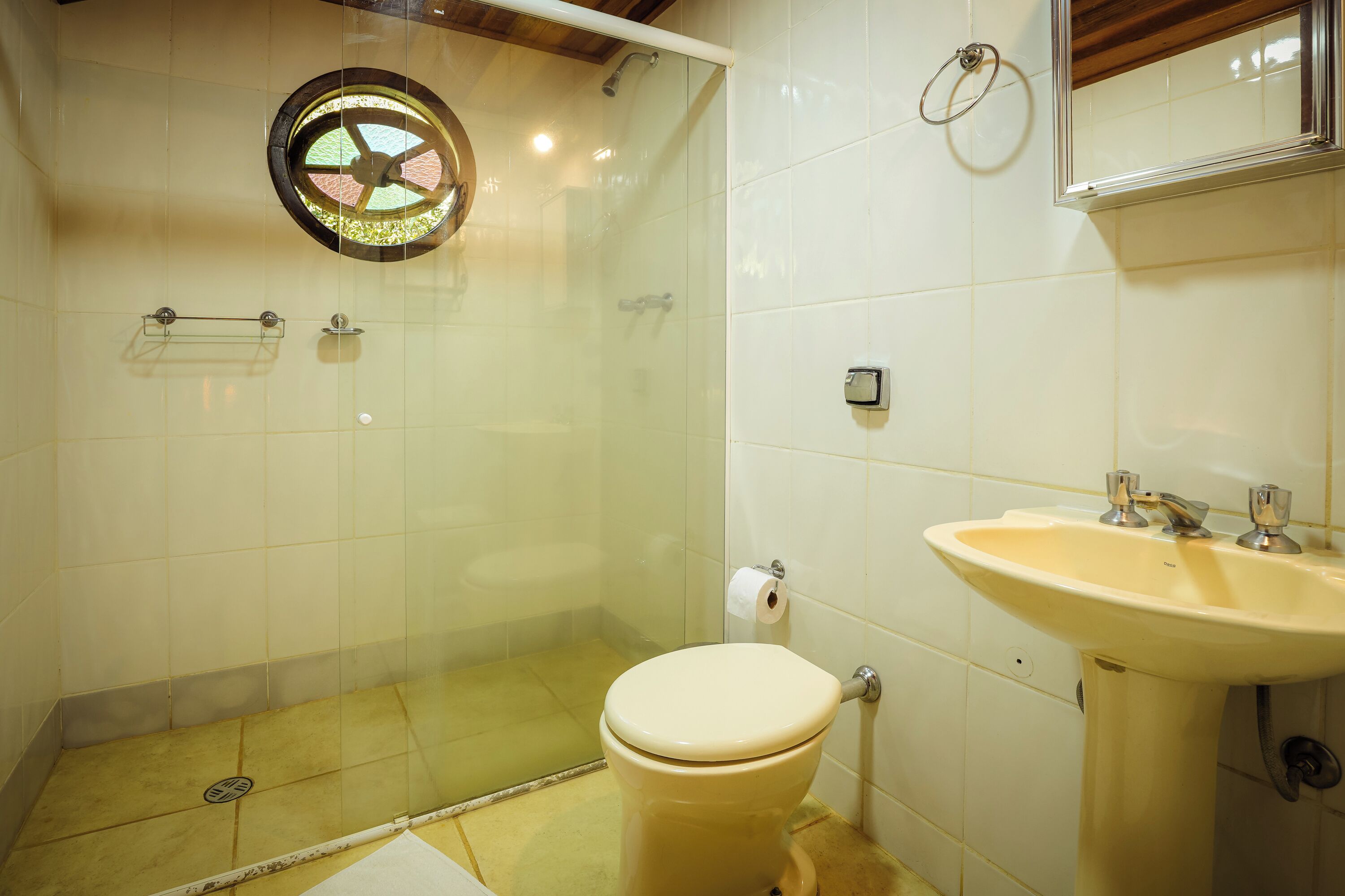 Een badkamer met toilet, wastafel en douchecabine met glazen wanden.