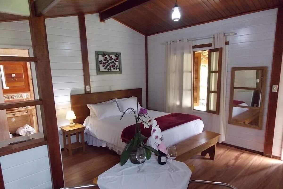 A bedroom with a bed, bedside table, lamp, and a mirror.