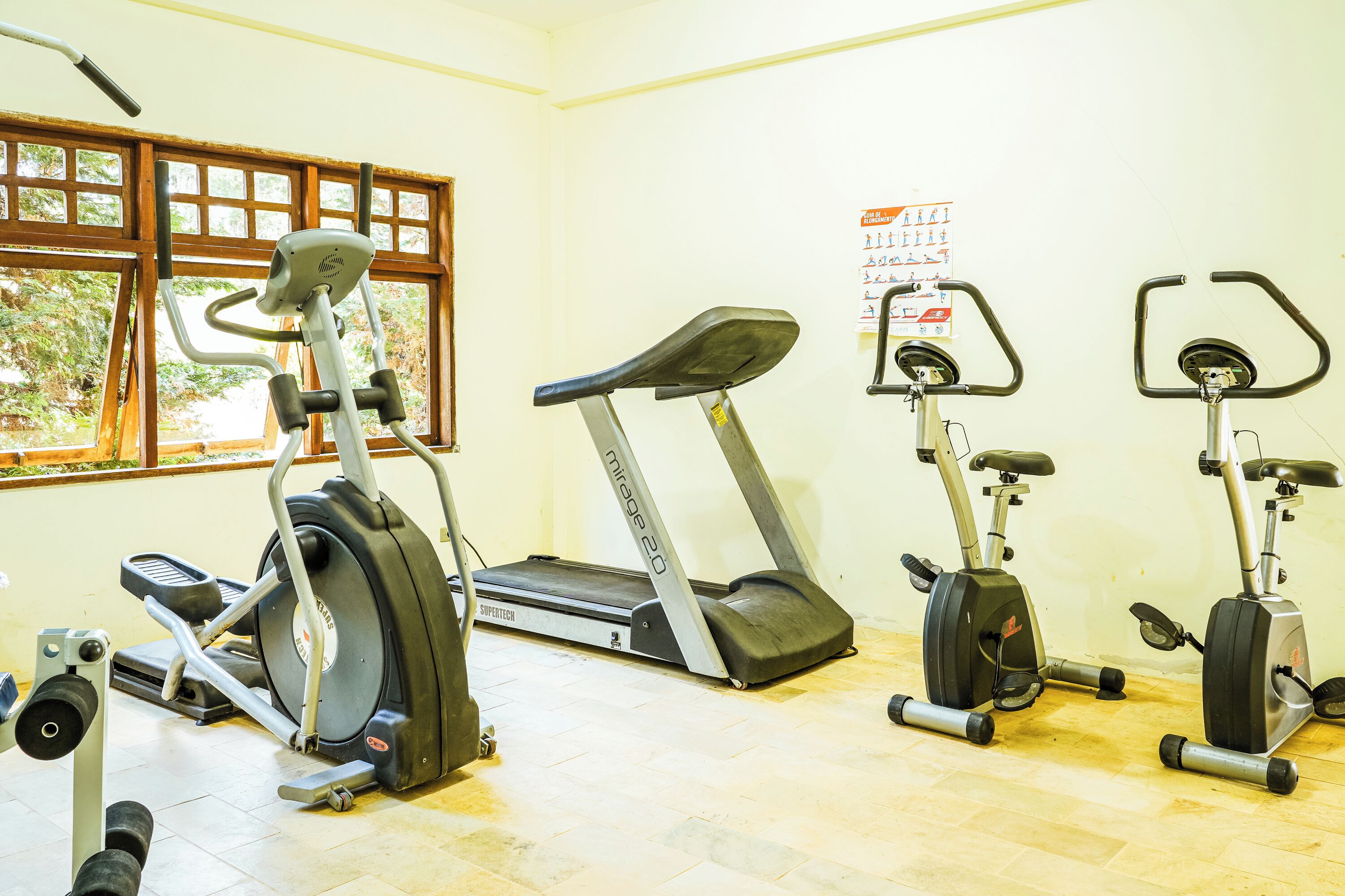 Een sportschool met loopbanden, elliptische trainers en een hometrainer.